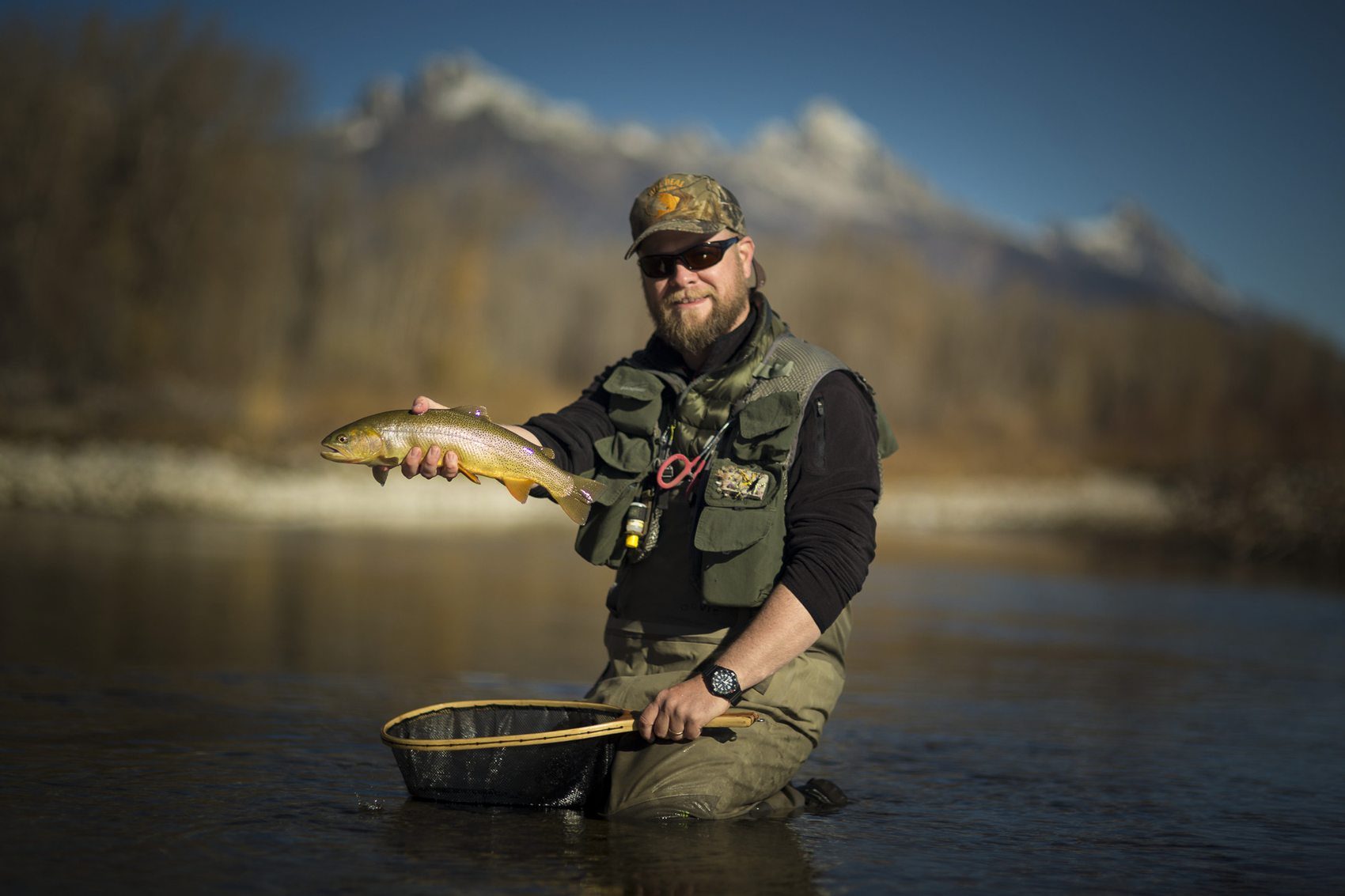 Fly fishing guide releasing a cutthroat trout