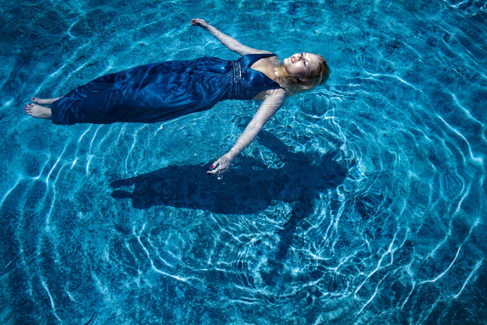 Overhead frame of a woman floating in a pool in an evening gown