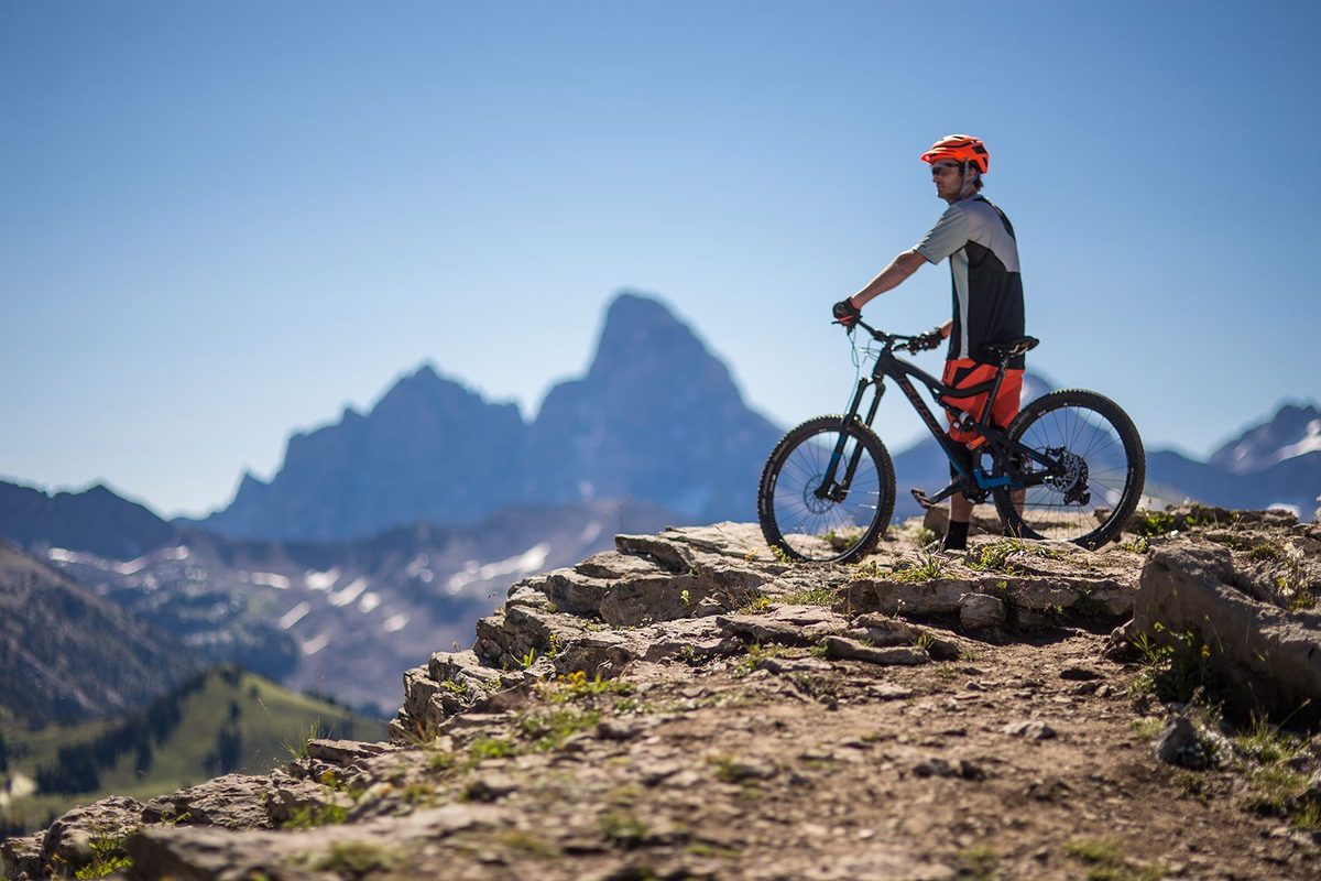 Mountain biker on a rock ridge with the Grand Teton behind