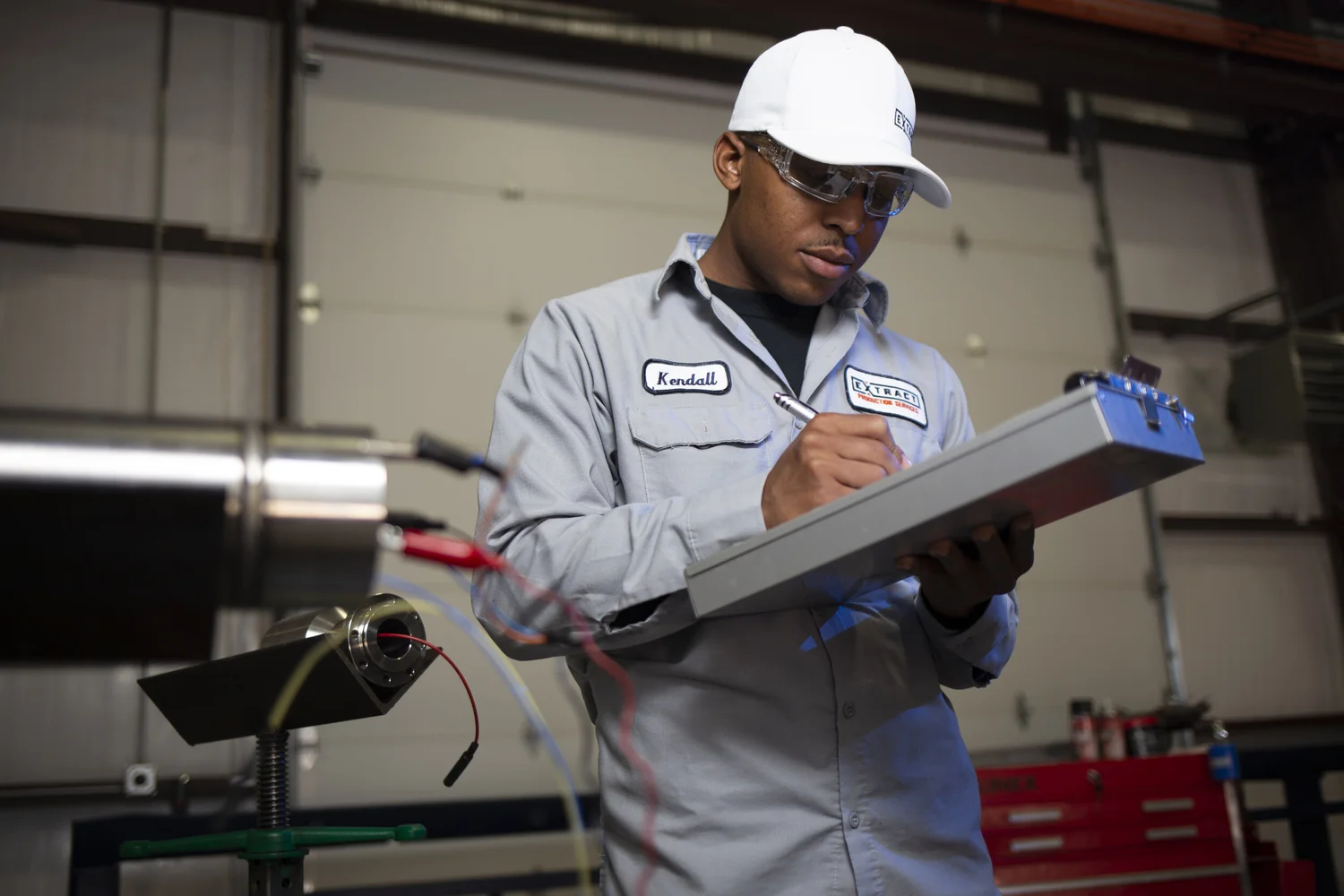 Fabricator reviewing work beside active shop equipment