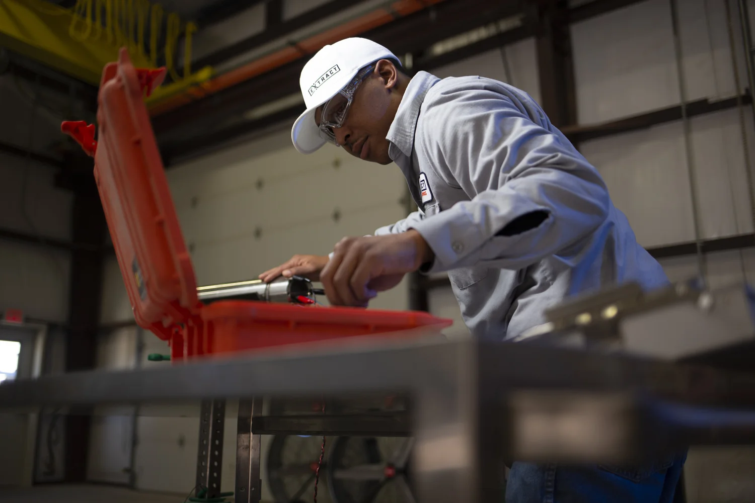 Fabricator working through a bright red industrial assembly