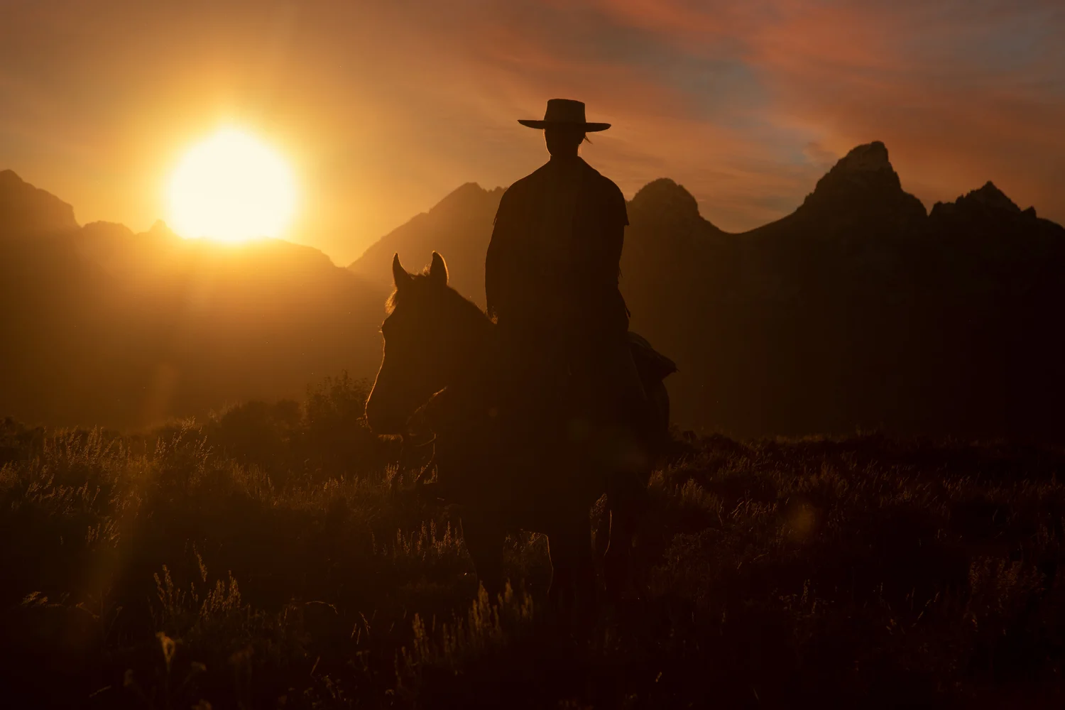 Horseback rider silhouetted against a Western sunset