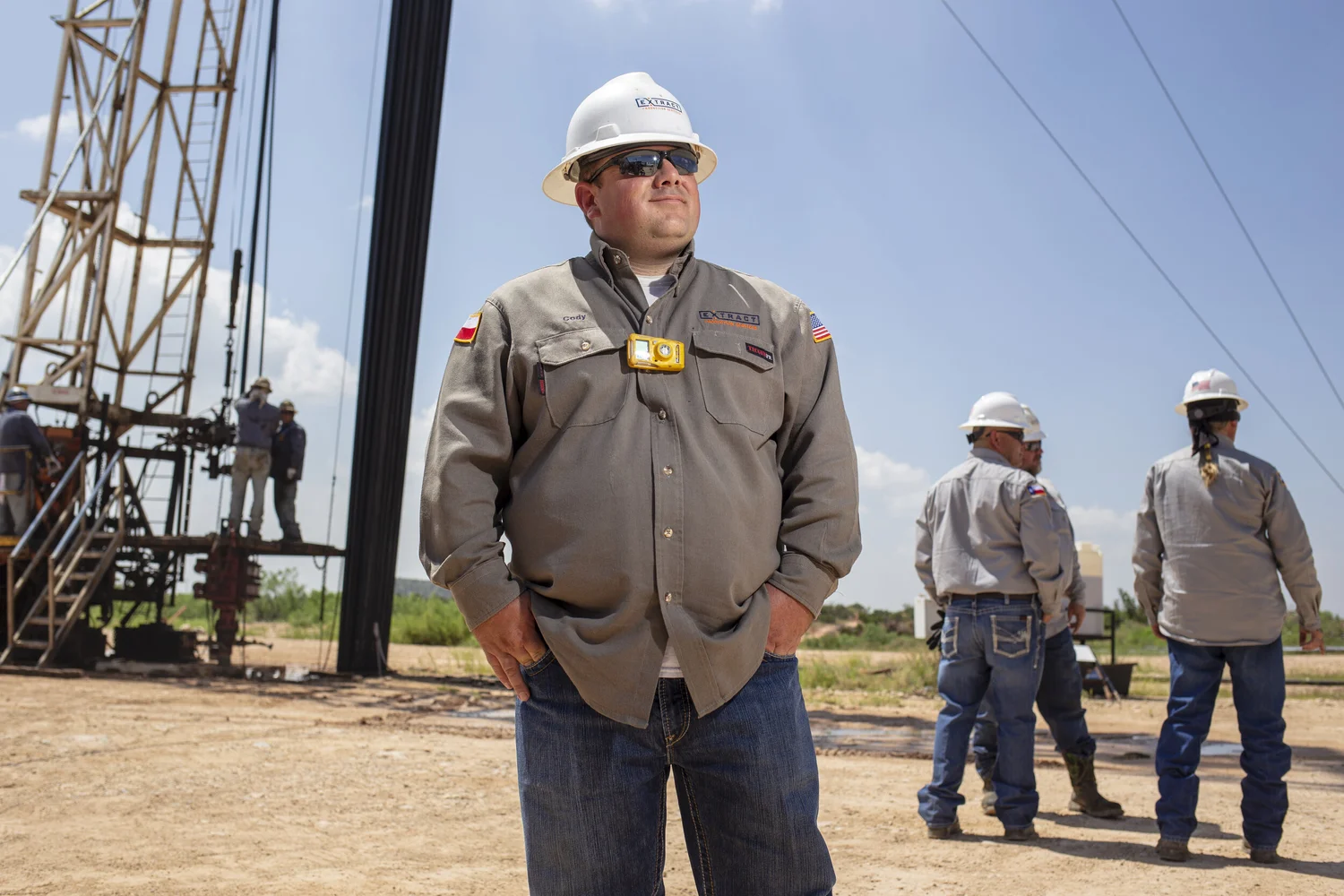 Three field workers photographed together beside operating equipment