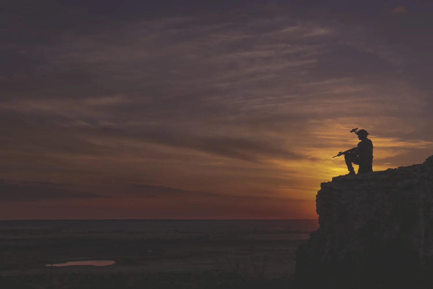 Small human figure held against a wide outdoor horizon at dusk