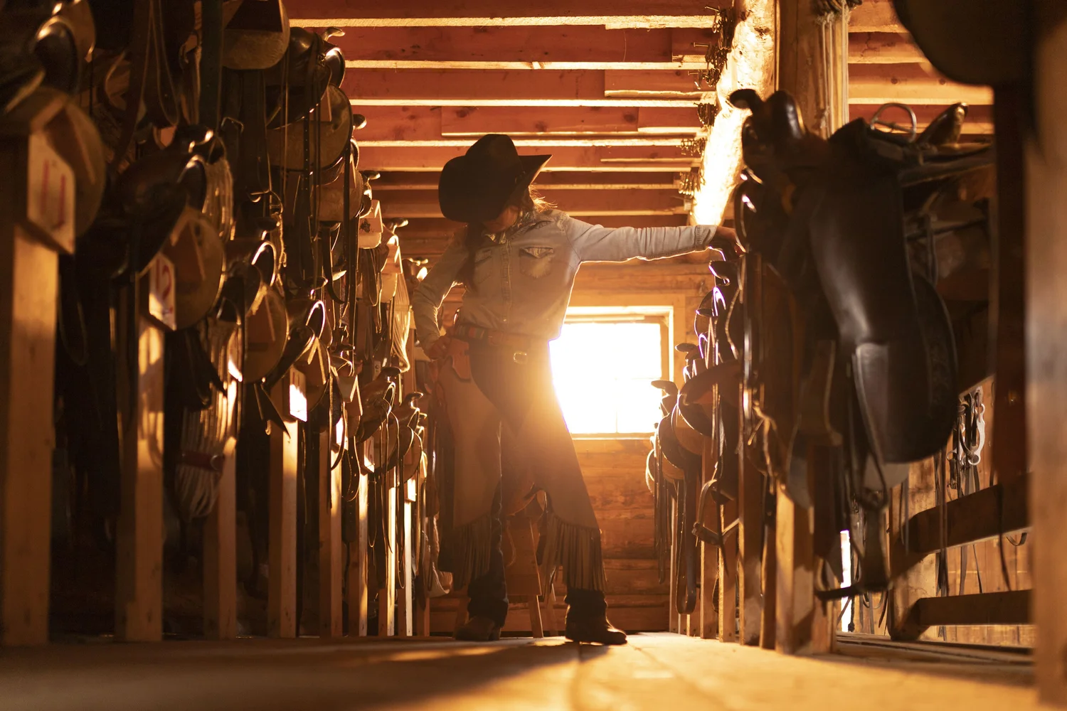 Western horsewoman inside a sunlit working stable