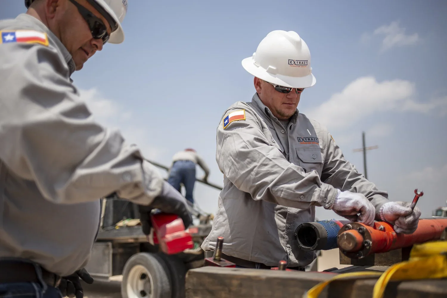Two field technicians working together on an industrial pipe assembly
