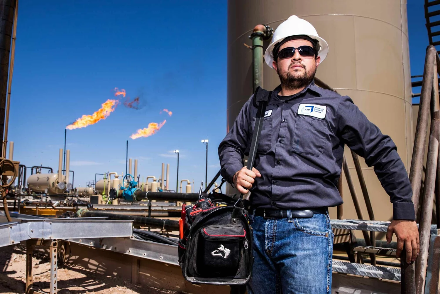 Oil field technician photographed with equipment and flare