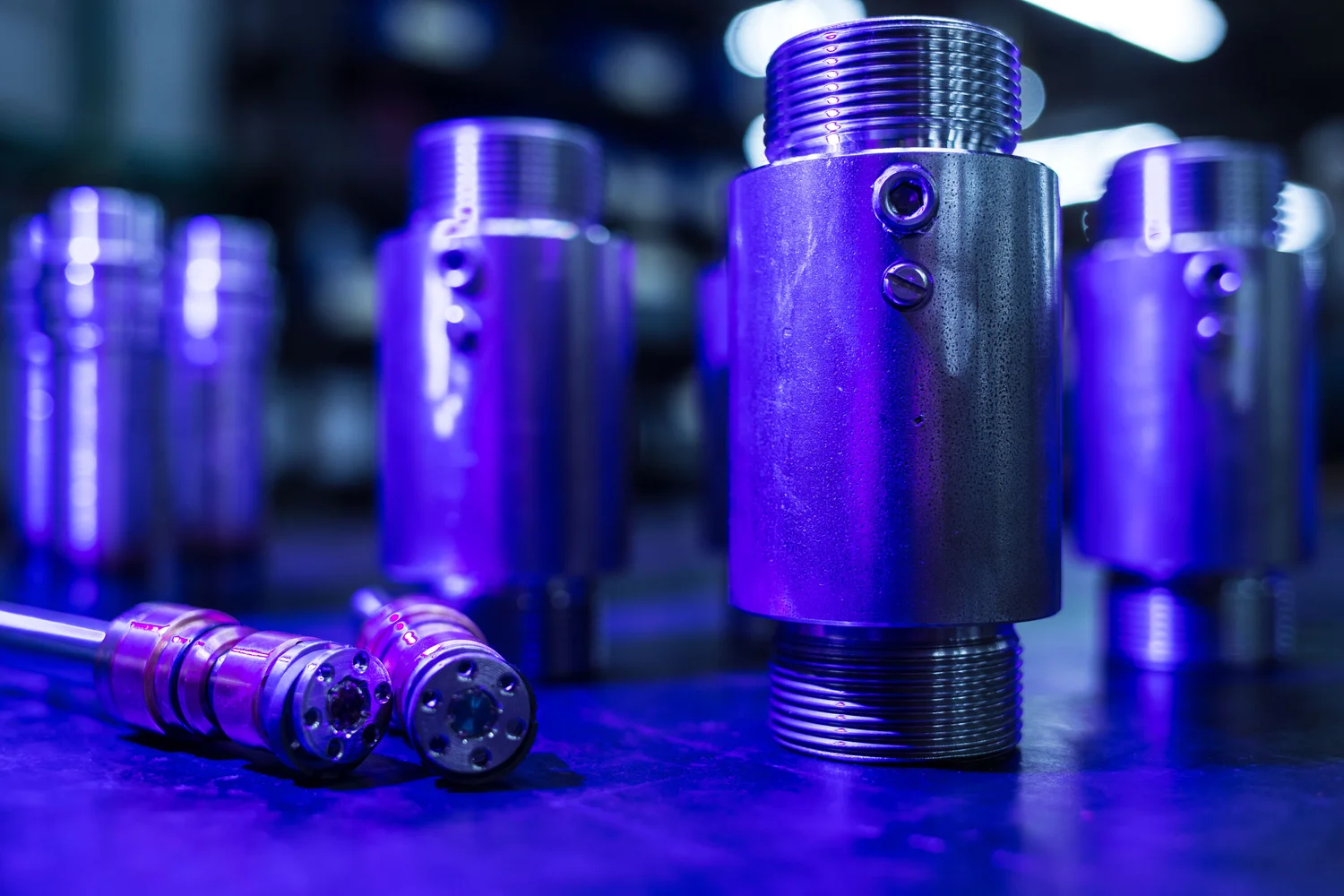 Machined components photographed in controlled blue and violet light
