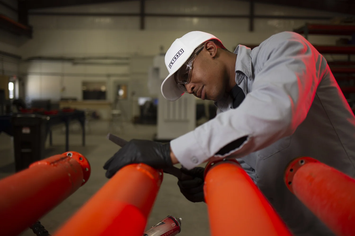 Technician working across a bank of bright red industrial pipe