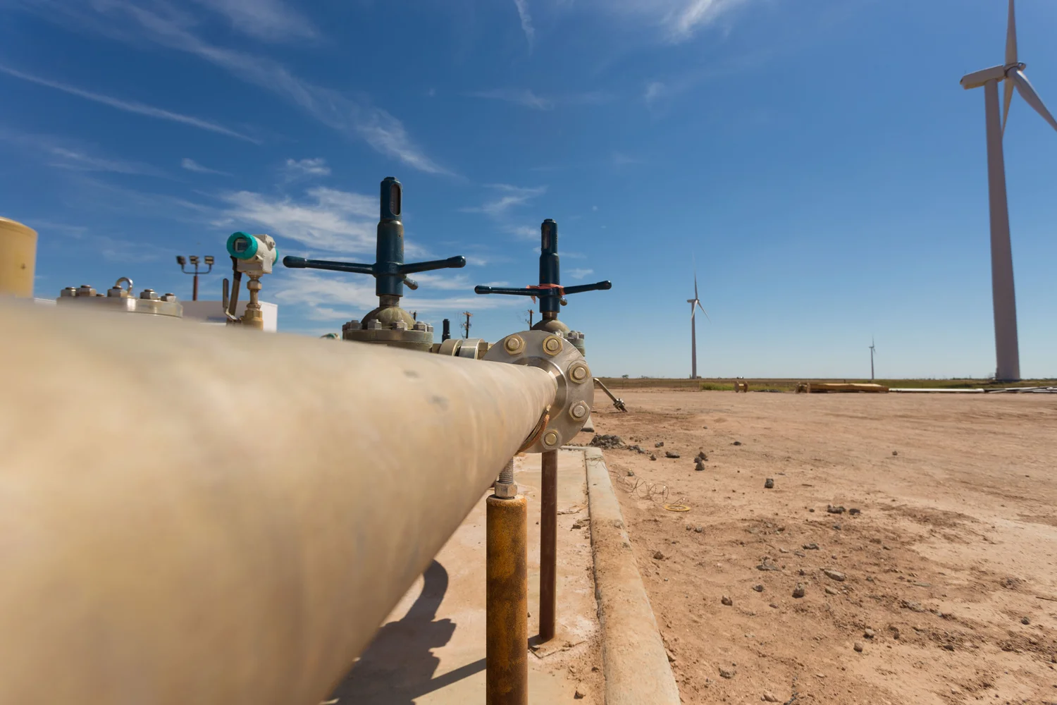 Industrial pipeline photographed in open country with wind turbines